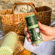Holding bottle of A bit Hippy Patchouli deodorant on beach background, aluminium free natural deodorant for sensitive skin.