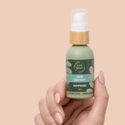 Hand holding A bit Hippy Hair Growth Serum 50ml bottle on peach background, natural formula with 2-Deoxy-D-Ribose, caffeine, rosemary oil, and sodium alginate to promote hair growth and thicker, fuller hair.