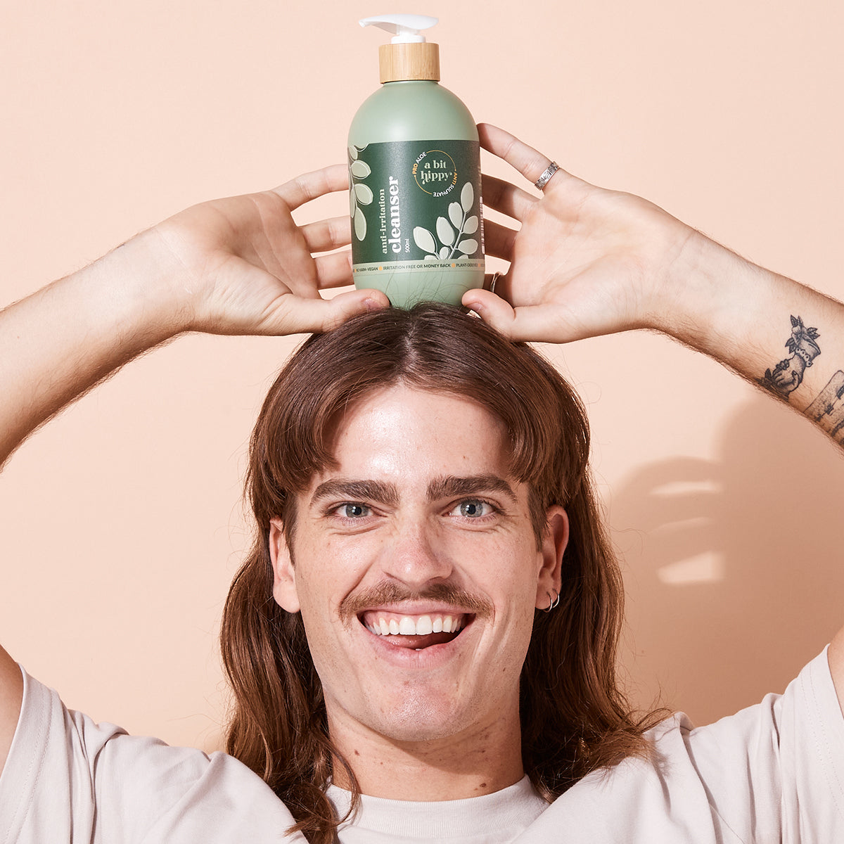 Model holding A bit Hippy Cleanser 500ml on head, aloe vera anti irritation cleanser for face and body, sulphate free formula