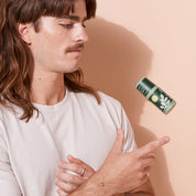 Man tossing a bottle of A bit Hippy Bergamont in the air on a peach background, natural aluminium free deodorant. 