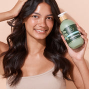 Smiling woman holding A bit Hippy Hair Growth & Volume Conditioner 500ml bottle on peach background, Phthalate free conditioner with Caffeine and Rosemary to promote hair growth and volume.