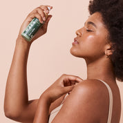 Woman applying A bit Hippy Face Mist onto face on peach background, refreshing face mist spray to prepare skin for moisturisers, sunscreen or makeup.