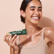 Smiling woman holding A bit Hippy Night cream against peach background. Overnight restoration for sentitive skin. 